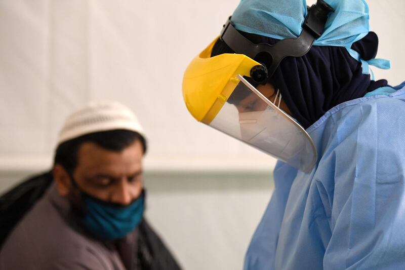 A health worker takes samples from foreign workers to check for the novel coronavirus at a testing centre in the Al Quaz area of Dubai, in the United Arab Emirates, on April 18, 2020. / AFP / KARIM SAHIB
