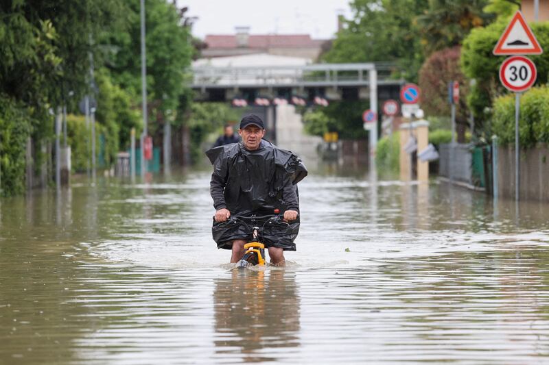 A man cycles through floodwaters after heavy rains hit Italy's Emilia Romagna region. Reuters