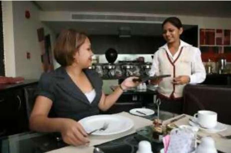 Abu Dhabi, UAE - October 16, 2008 - A diner takes the bill from a waitress at Memories Restaurant inside Kingsgate Hotel. (Nicole Hill / The National)  *** Local Caption ***  NH Kingsgate07.jpg