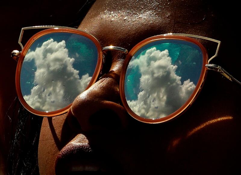 Passing clouds are reflected in a fan's sunglasses during an NCAA college football game between Kansas and Rutgers in Lawrence, Kansas. AP