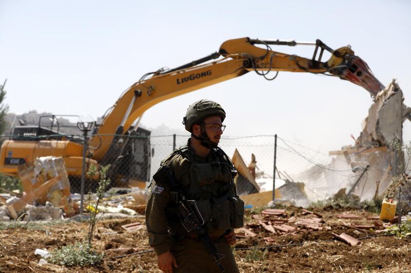 An Israeli soldier stands guard as the restaurant is flattened. EPA