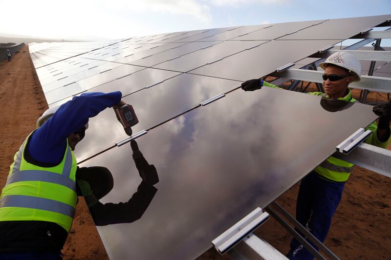 Workers install a solar panel at a photovoltaic solar park on the outskirts of the coastal town of Lamberts Bay, South Africa. AP