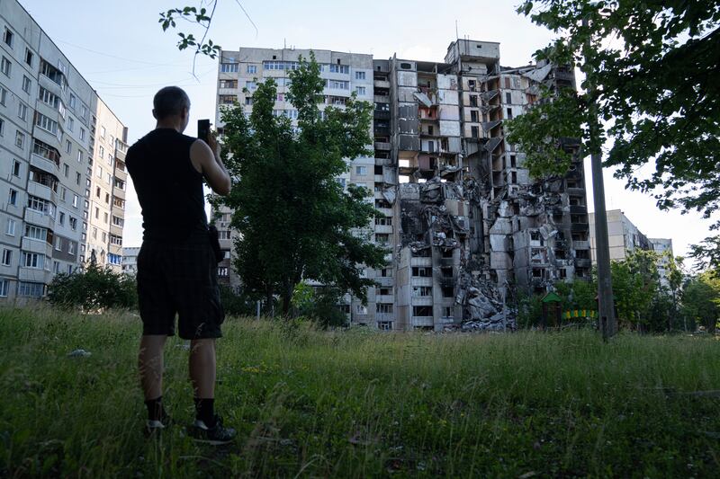 A man takes a picture with his phone of a building that had been destroyed in a Russian attack in Kharkiv. AP