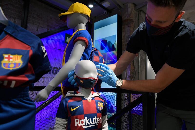 An employee places a mask with the logo of FC Barcelona on a mannequin at the FC Barcelona store. AFP