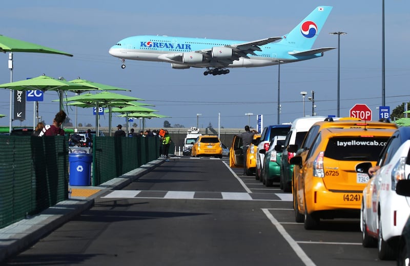 LOS ANGELES, CALIFORNIA - NOVEMBER 06: A Korean Air plane lands as taxis are lined up at the new 'LAX-it' ride-hail passenger pickup lot at Los Angeles International Airport (LAX) on November 6, 2019 in Los Angeles, California. The airport has instituted a ban on Lyft, Uber and taxi curbside pickups as airport construction increases during a modernization program. Passengers have complained of long wait times and confusion at the pickup area, especially during peak hours. Passengers must depart their terminal and then ride a shuttle bus or walk to the separate pickup lot.   Mario Tama/Getty Images/AFP