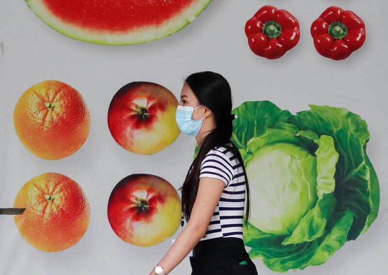 A woman wearing a protective mask walks outside a mall in Manila, Philippines. AP