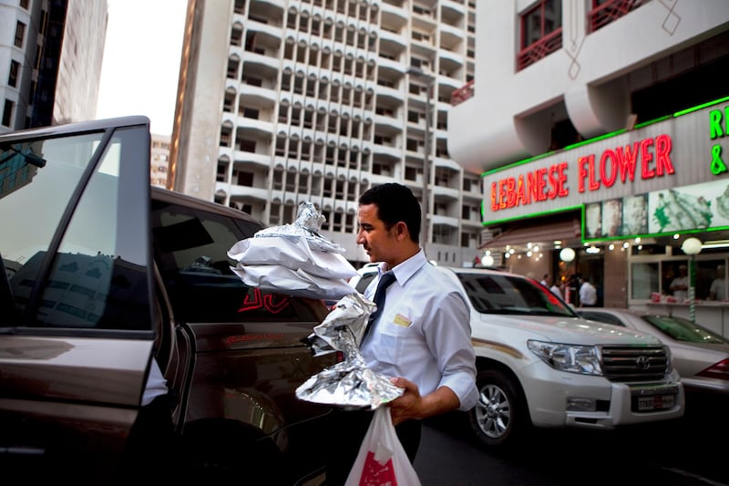Waiter Nadi Ahmad Shater carries full platers to a car as he works during the iftar rush hour at the Lebanese Flower restaurant, a 24-year-old institution in the Khalidiya neighborhood in Abu Dhabi on Monday, August 1, 2011, the first day of Ramadan. (Silvia Razgova/The National)

