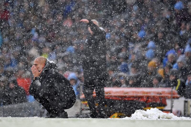 Pep Guardiola (L) crouches down as he watches Manchester City play West Ham. Getty