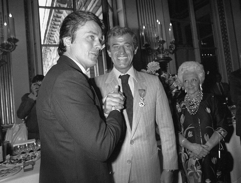 In this photo taken on September 23, 1980, Jean-Paul Belmondo, second left, shakes hands with French actor Alain Delon, left, after being awarded the Legion d'Honneur during a ceremony at the Ministry of Culture in Paris. His mother Madeleine Belmondo looks on. AFP