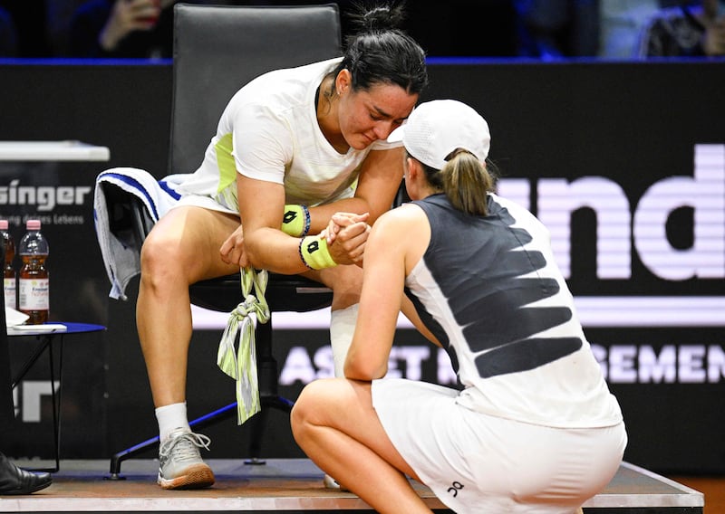 A tearful Ons Jabeur shakes hands with Iga Swiatek after the Tunisian was forced to retire injured from their Stutttgart Open semi-final, on April 22, 2023. AFP