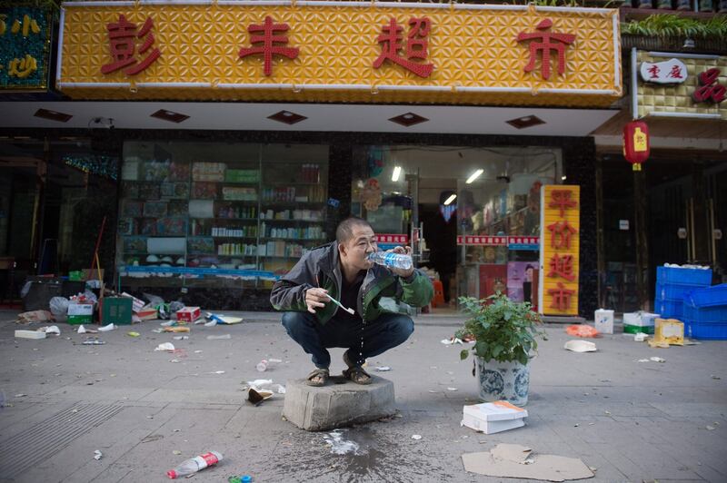 TOPSHOT - A resident brushes his teeth outside his shop after an earthquake in Zhangzha in southwest China's Sichuan province on August 10, 2017. 
The 6.5-magnitude earthquake struck Sichuan province late on August 8, tearing cracks in mountain highways, triggering landslides, damaging buildings and sending panicked residents and tourists fleeing into the open. / AFP PHOTO / Nicolas ASFOURI