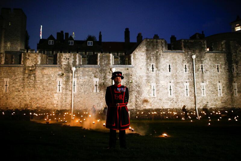A Yeoman of the Guard stands among lit torches that are part of the installation 'Beyond the Deepening Shadow' at the Tower of London. Reuters