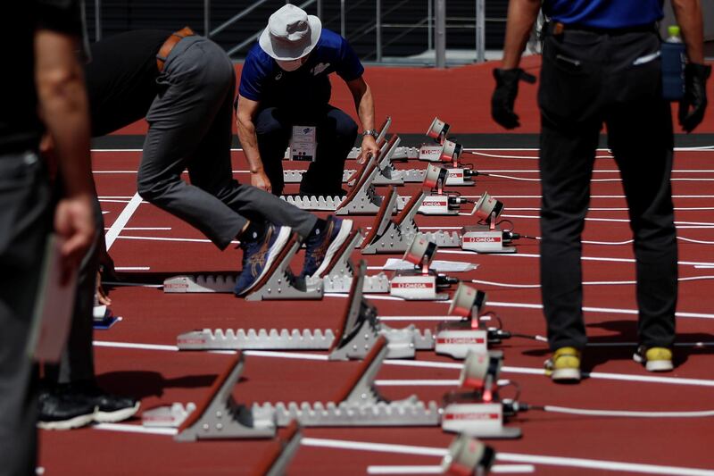 Officials check on starting blocks before the start of the morning session of the athletics test event. Reuters