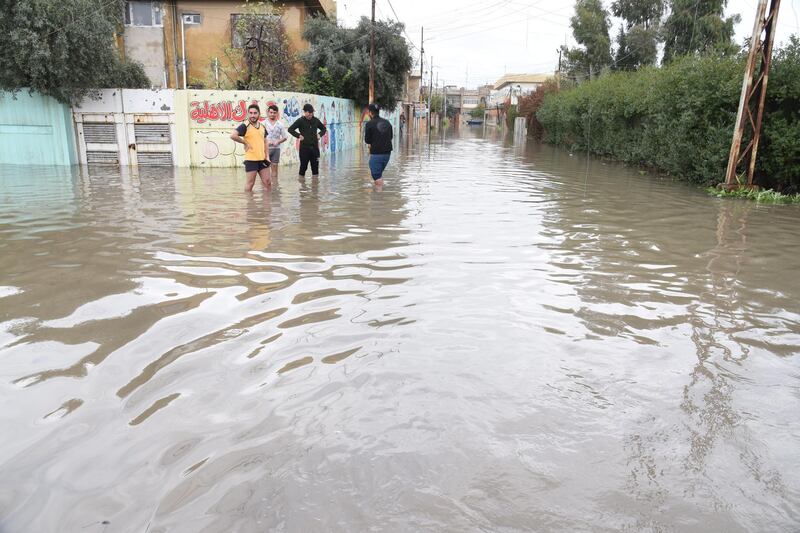 Iraqis stand amid a flooded street in Mosul. EPA