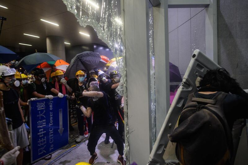 Protesters smashing glass doors and windows of the government headquarters in Hong Kong on the 22nd anniversary of the city's handover from Britain to China.   AFP