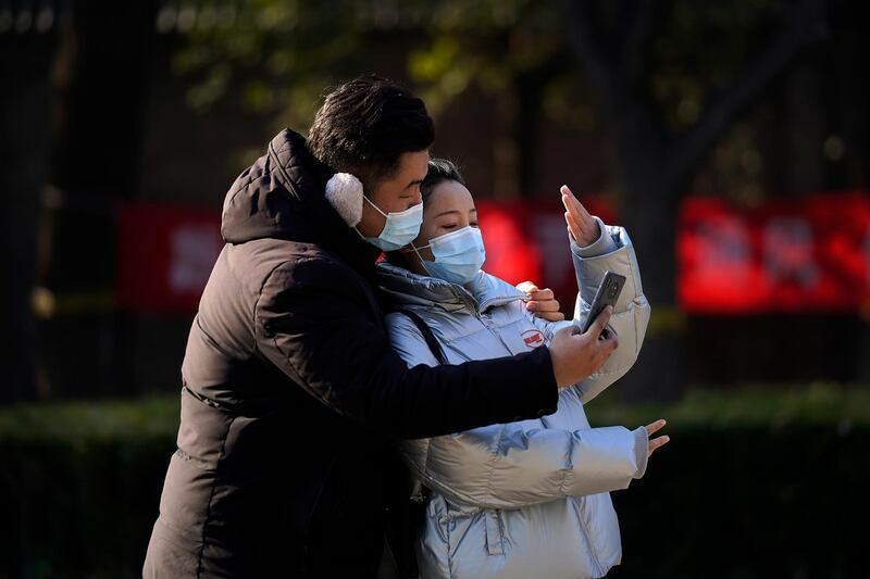 A couple wearing face masks to help curb the spread of the coronavirus take a selfie near the drum tower, a tourist spot in Beijing. AP Photo