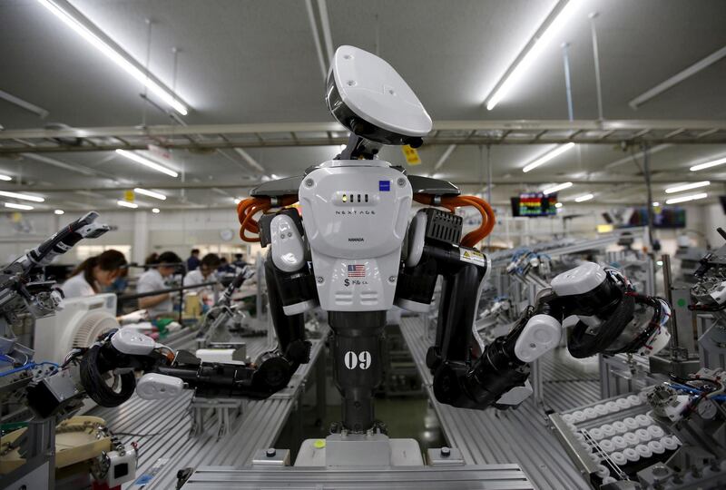 FILE PHOTO: A humanoid robot works side by side with employees in the assembly line at a factory of Glory Ltd., a manufacturer of automatic change dispensers, in Kazo, north of Tokyo, Japan, July 1, 2015. Japanese firms are ramping up spending on robotics and automation, responding at last to premier Shinzo Abe's efforts to stimulate the economy and end two decades of stagnation and deflation. Picture taken July 1, 2015. REUTERS/Issei Kato/File Photo