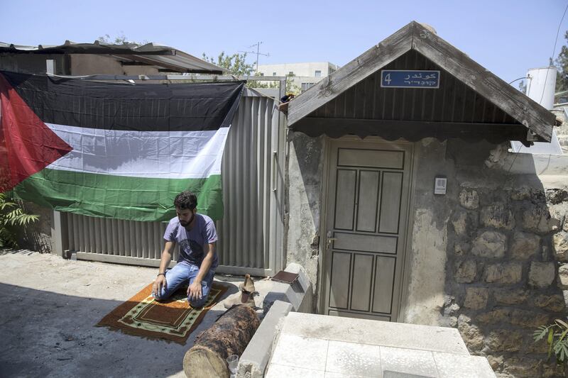 A man is seen praying by a Palestinian flag hung on a home next to the house of the  Shamasneh family during a support protest  Friday noon prayer in the East Jerusalem neighborhood of Sheik Jarrah on August 11,2017.

When the Shamasne family first moved into their home  in the 1960s, East Jerusalem was controlled by Jordan and their monthly rent was paid to  Jordanian authorities but since  Israel annexed East Jerusalem in 1967, the Shamasne family has paid their rent to Israel's general custodian in order to remain in the building.
The family claims that their payments were suddenly rejected in 2009 , and they were informed that the property had been claimed by Israeli Jews whose ancestors had lived there decades previously.Although the family has spent years fighting to remain in the home , the Israeli high court has ruled that the family must evacuate the home before August 9. (Photo by Heidi Levine for The National).