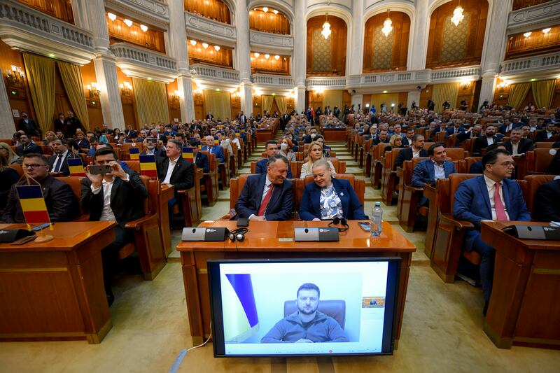 Romanian politicians listen to President Zelenskyy’s speech by video link, on a screen in the parliament in Bucharest. AP