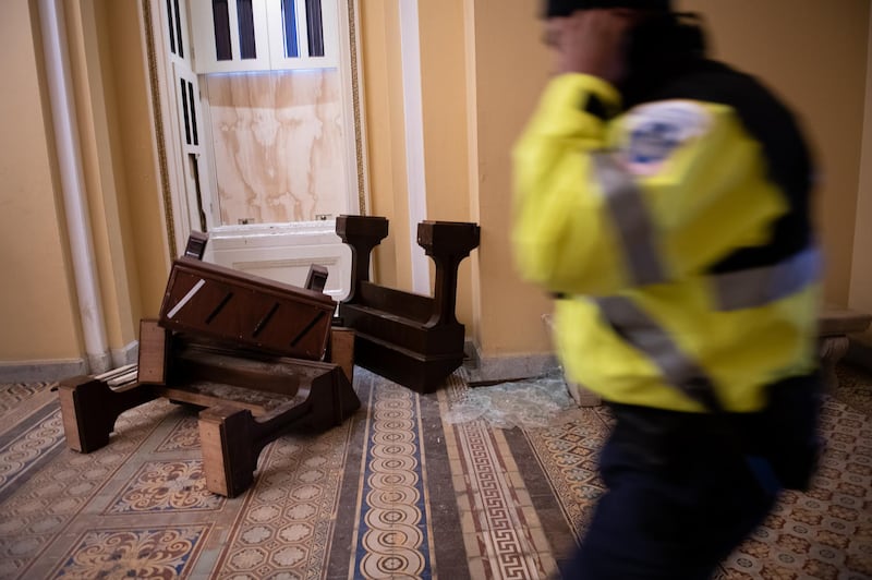 A US Capitol police officer passes in front broken furniture and shattered glass at the Capitol building. Bloomberg