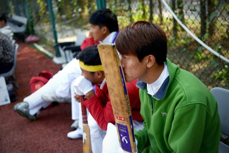 Chinese cricketers, above, watching a match played on an AstroTurf pitch in Beijing. Wang Zhao / AFP