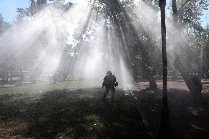 A man is silhouetted against mist caused from police water cannon used to disperse anti-government demonstrators protesting over inequality in Santiago, Chile. AP Photo