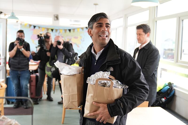 Mr Sunak speaks with a cafe worker as he picks up breakfast for the media at a cafe in Cornwall. PA