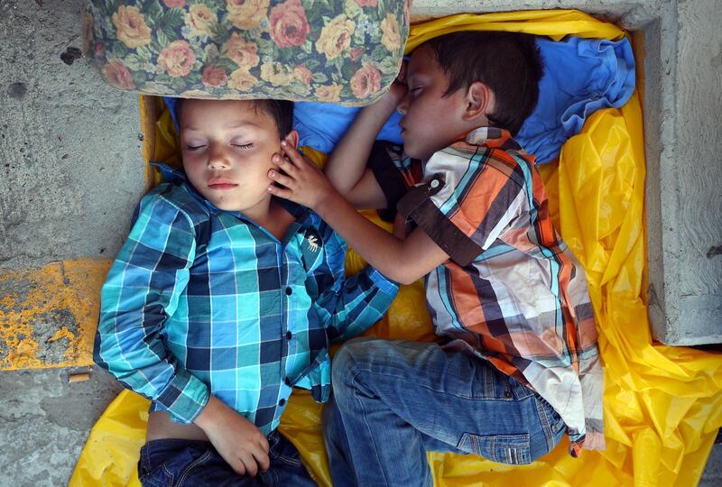 Migrant twin brothers, Justin Mauricio and Justin Duan, aged 7, rest on the roadside in Tapanatepec, Mexico, as they travel as part of a caravan of thousands from Central America en route to the US. Reuters