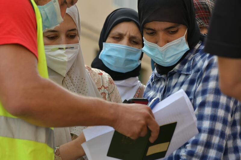 Policemen check passports of Moroccan woman, stranded in Spain since the closure of borders in mid-March to tackle the coronavirus, in the Spanish enclave of Ceuta. Hundreds of Moroccans stranded in the Spanish enclaves of Ceuta and Melilla since the border with Morocco was closed due to coronavirus pandemic, will be repatriated to their country, Spanish authorities announced. AFP