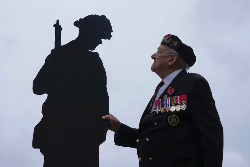 Normandy veteran Ken Hay poses with an art installation of life-sized silhouettes of servicemen, by community project Standing with Giants, at Kensington Gardens in London. AP