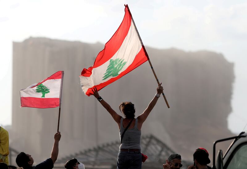 Demonstrators wave Lebanese flags during protests near the site of a blast at Beirut's port area.  Reuters