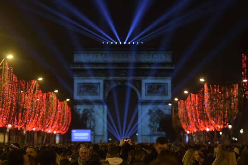 Revellers gather near the Arc de Triomphe at the Champs-Elysees for New Year's celebrations in the French capital Paris on December 31, 2018.  A fireworks display and sound and light show under the theme "fraternity" is set to go ahead on the Champs-Elysees despite plans for further "yellow vest" anti-government protests at the famed avenue. / AFP / Lucas BARIOULET         
