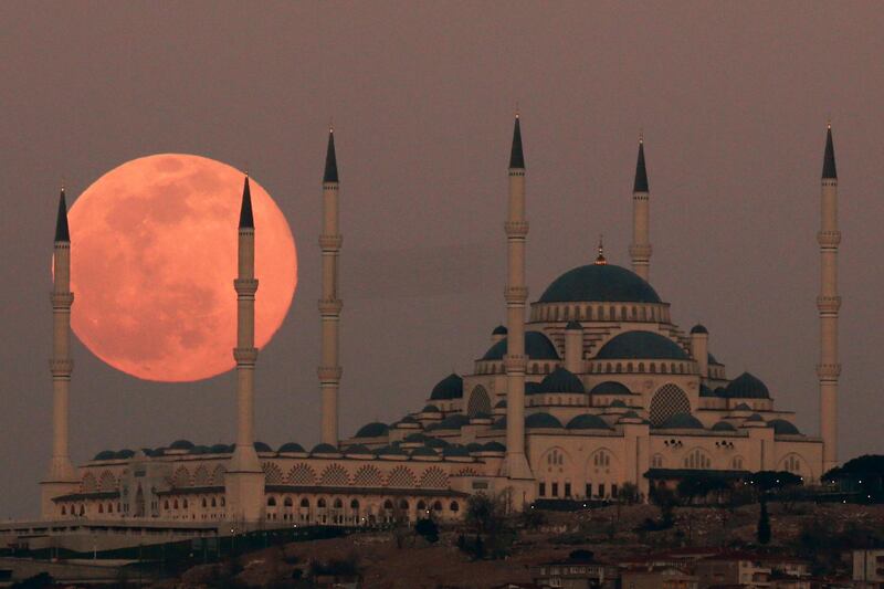 The moon rises over the sky in the Turkish capital of Istanbul with the Camlica Mosque, the largest in the country, seen in the backdrop. AP Photo