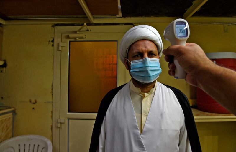 A volunteer checks the temperature of Muslim Shiite clergyman at a religious community centre in Malkaiya village, northwest of the Bahraini capital Manama. AFP