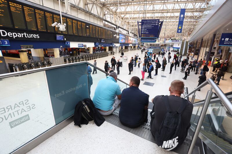 Passengers wait for trains at Waterloo station in London. PA