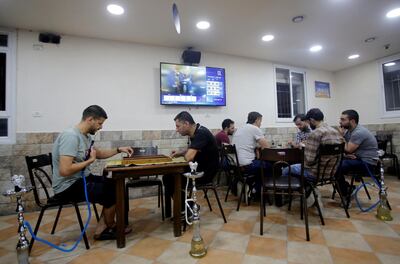 Palestinians play a board game and cards as television screen displays news about the results of the Israel's parliamentary election, in a coffee shop in Hebron in the Israeli-occupied West Bank September 17, 2019. REUTERS/Mussa Qawasma