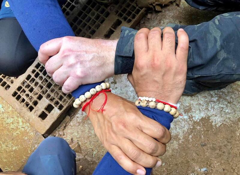 Rescuers lock their hands on a photo posted on Thailand Navy SEAL Facebook page. AP
