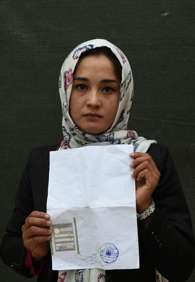 In this photo taken on October 11, 2018, Kabul university student Zahra Faramarz, 21, poses for a picture as she holds her ID card or Tazkira registered to vote in the upcoming parliamentary election, in Kabul. Bloody violence has forced thousands of polling centres to close and stopped millions of people from registering to vote. But war-torn Afghanistan's long-delayed legislative election will still go ahead on October 20, officials say. Almost nine million people are eligible to vote in the ballot, which is more than three years late and largely funded by the international community.
 / AFP / WAKIL KOHSAR
