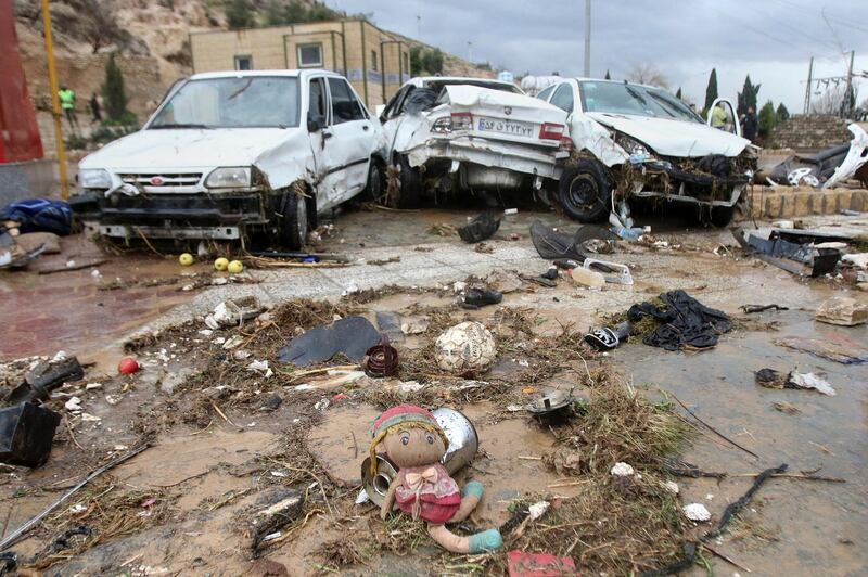 A child's doll lies in front of destroyed cars after a flash flood in the southern city of Shiraz. AP Photo