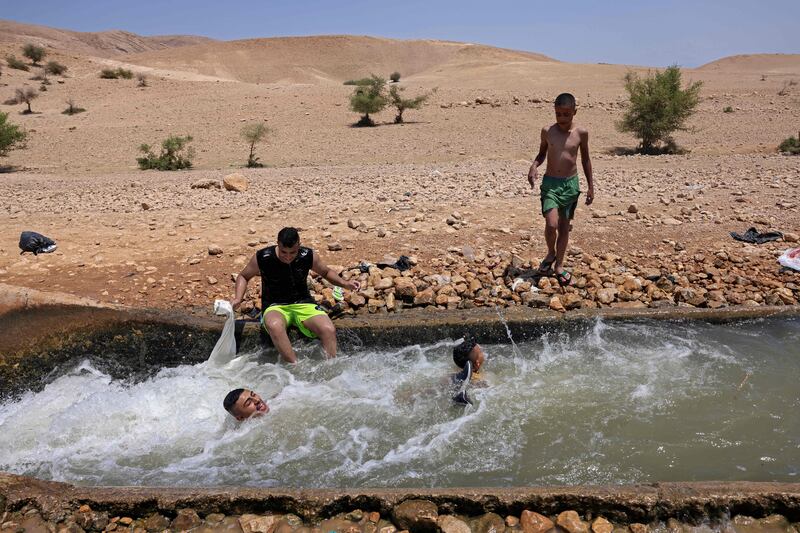 Palestinians cool down in a water canal in the village of al-Auja in the occupied West Bank. AFP