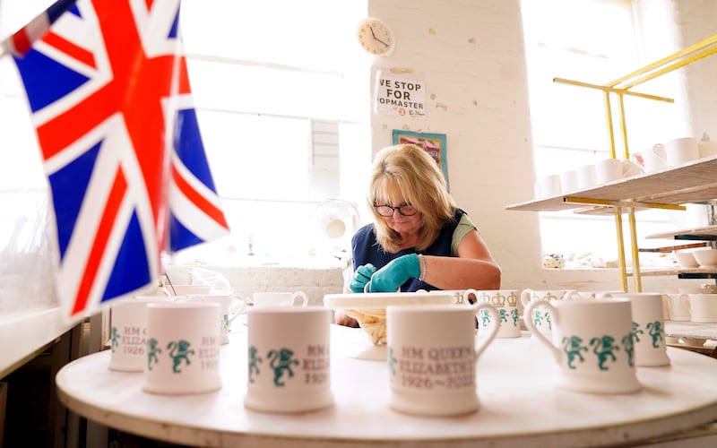 Joyce Buckley, a sponge decorator at Emma Bridgewater pottery in Stoke-on-Trent, Staffordshire, paints a commemorative mug. PA