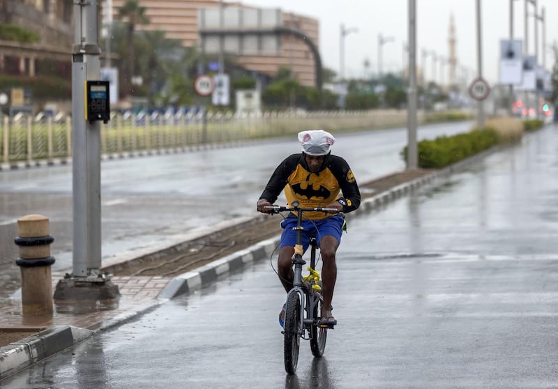 Dubai, United Arab Emirates - Reporter: N/A: Weather. A cyclist rides with a bag on his head to stay dry as the rain comes down in Dubai. Saturday, March 21st, 2020. Jumeirah, Dubai. Chris Whiteoak / The National