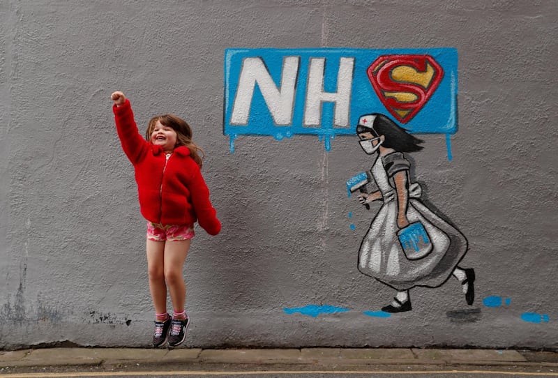 Lilly Davenport poses for her dad infront of a mural in tribute to the NHS painted by artist Rachel List in Pontefract. Reuters