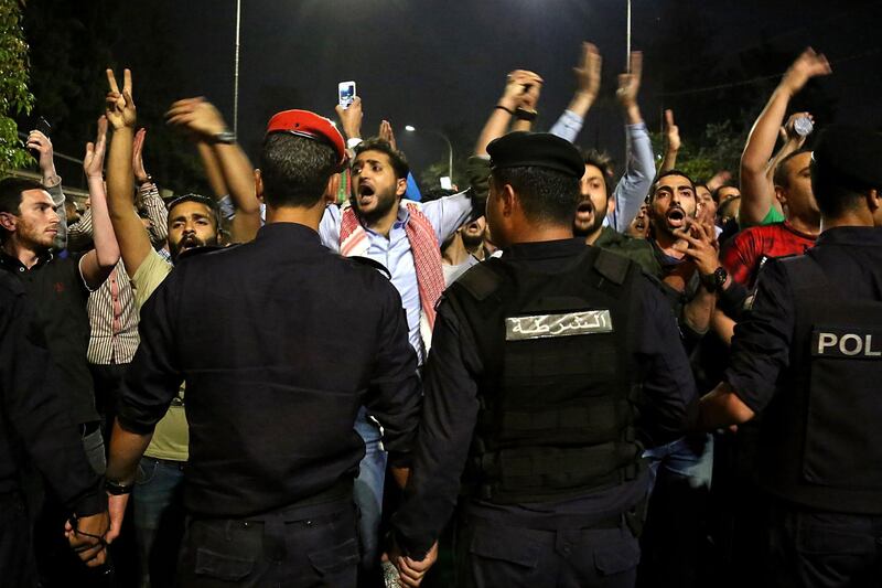 Demonstrators confront anti-riot policemen as they protest against against a proposed income tax draft law in front of the Prime Minister's office in Amman, late on June 1, 2018. Hundreds of Jordanians demonstrated in the capital Amman for a third consecutive day against a proposed income tax draft law aimed at widening the base of tax payers. / AFP / STRINGER
