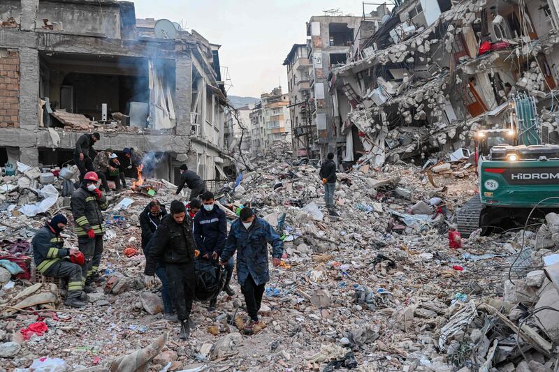 People carry a bodybag as residents wait for their relatives to be pulled out from the rubble in Hatay. AFP