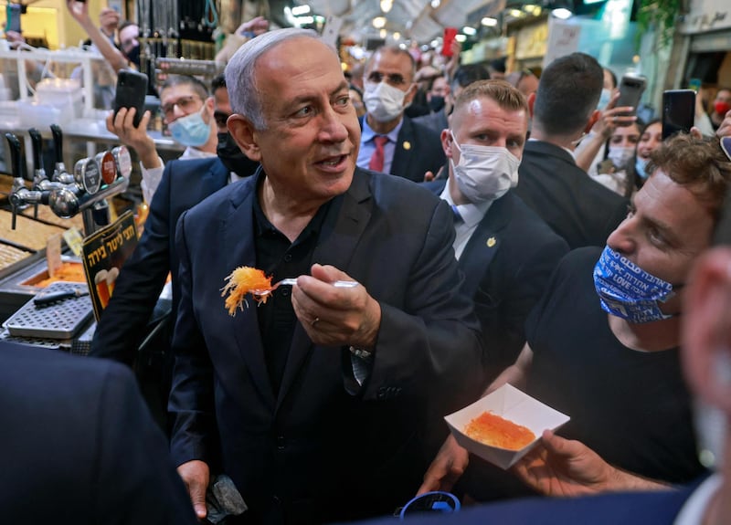 Israeli Prime Minister Benjamin Netanyahu eats dessert from a stall as he tours the Mahane Yehuda market in Jerusalem. AFP