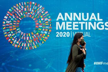 A woman walks past a promotional poster for the virtual 2020 Annual Meetings outside the International Monetary Fund at their headquarters in Washington, DC on October 13, 2020. AFP 