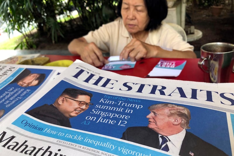 FILE - In this May 11, 2018, file photo, a news vendor counts her money near a stack of newspapers with a photo of U.S. President Donald Trump, right, and North Korea's leader Kim Jong Un on its front page  in Singapore. U.S. Weeks from his North Korea summit, President Donald Trump is staring down a dealmakerâ€™s worst nightmare: overpromising and under-delivering. (AP Photo/Wong Maye-E)