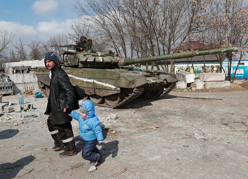 Mariupol residents walk past a tank belonging to pro-Russian forces in the besieged southern port city. Reuters