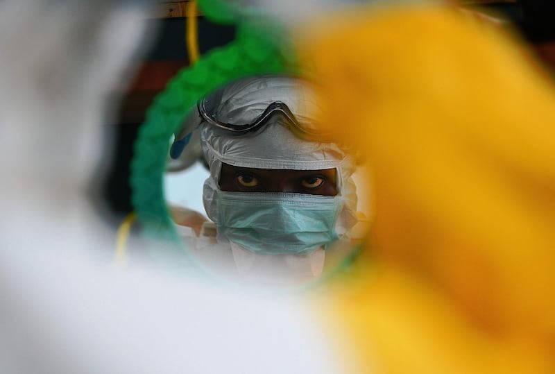 An MSF medical workers check their protective clothing in a mirror at an MSF facility in Kailahun, epicentre of the world's worst Ebola outbreak, on August 15, 2014. AFP